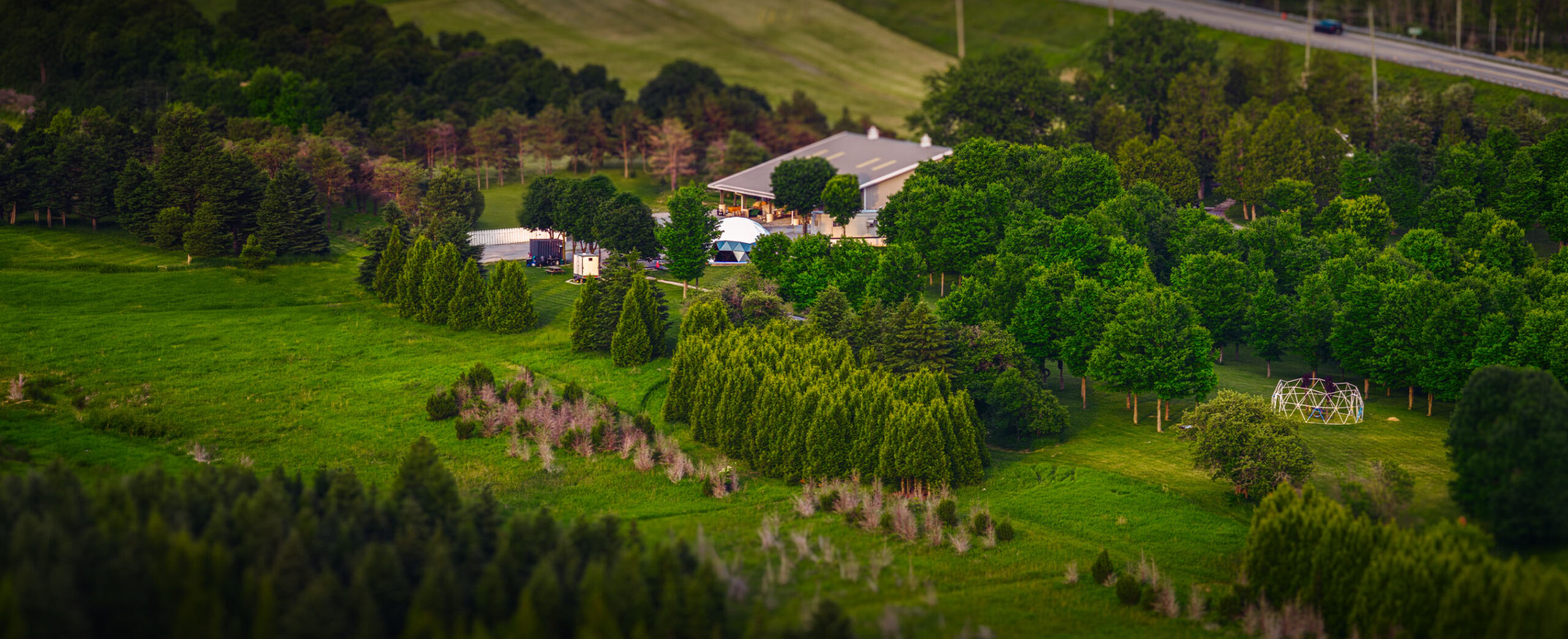 Aerial view of a rural site with fields, trees and buildings in AlteX drone-training promotional photography